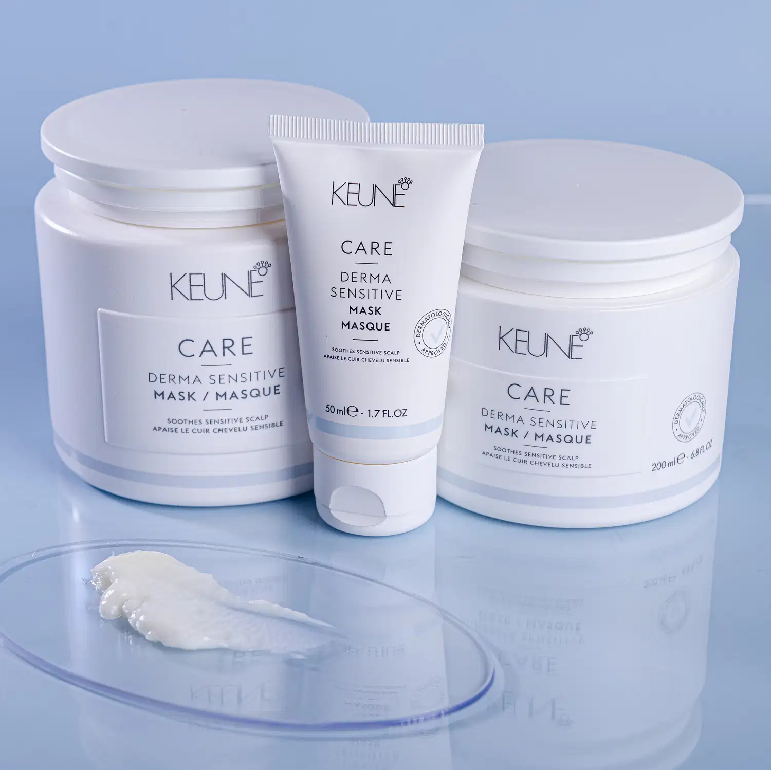 Produtos de cuidados capilares da marca Keune, incluindo máscaras de tratamento dermatologicamente sensíveis em embalagens brancas e azuis, com informações sobre os benefícios do produto impressas nos rótulos.