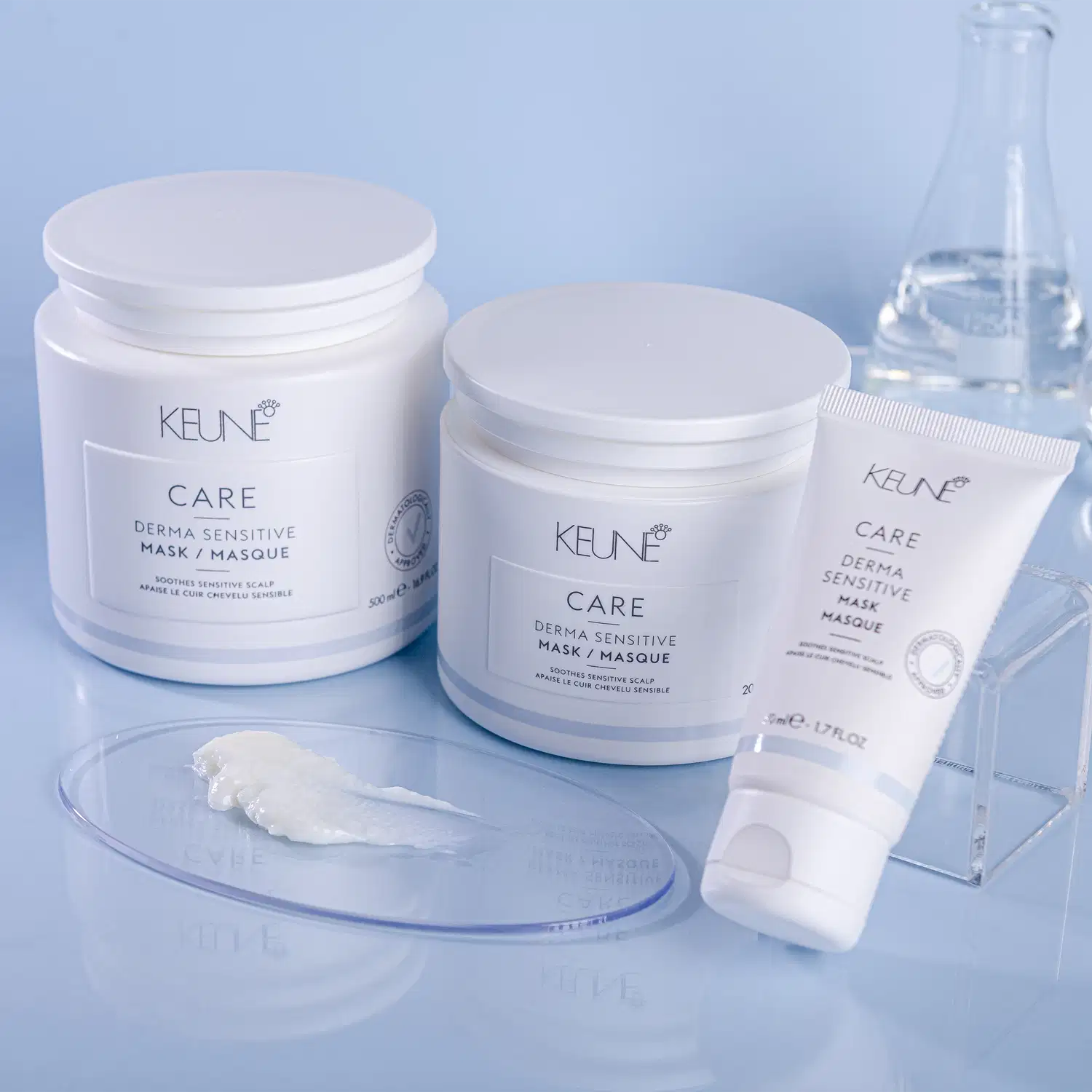 Produtos de cuidados capilares da marca Keune, incluindo uma máscara dermatológica sensível em embalagem branca e um tubo de máscara dermatológica sensível, com detalhes em azul claro.