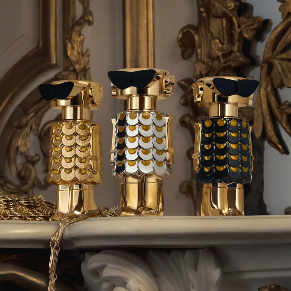 Frasco de perfume dourado e prateado com design escamado, evocando uma aparência luxuosa e sofisticada, típica da marca Paco Rabanne.