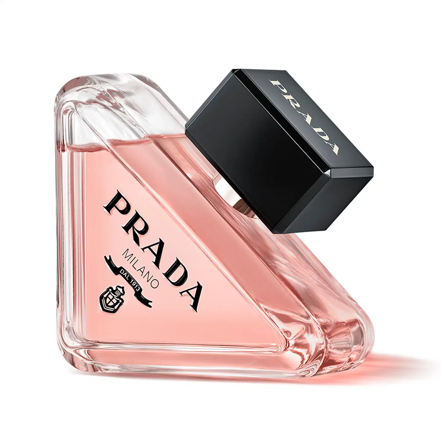 Frasco de perfume Prada com design triangular em vidro transparente, contendo líquido de cor rosa clara. O rótulo preto destaca o nome da marca "PRADA" em letras brancas.