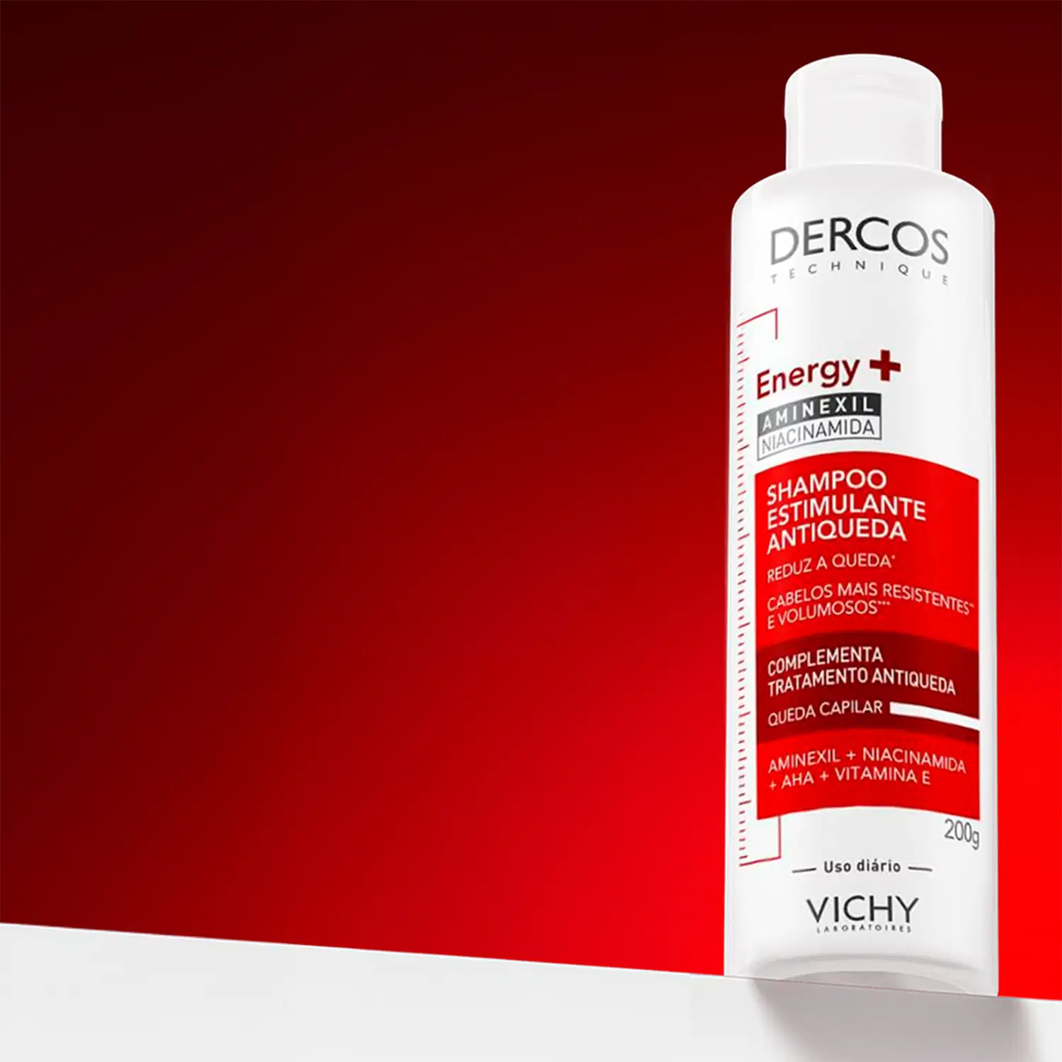 Frasco branco de shampoo estimulante da marca Dercos, com rótulo vermelho e branco destacando os ingredientes Aminexil e Niacinamida, que promovem a redução da queda de cabelo e volume.