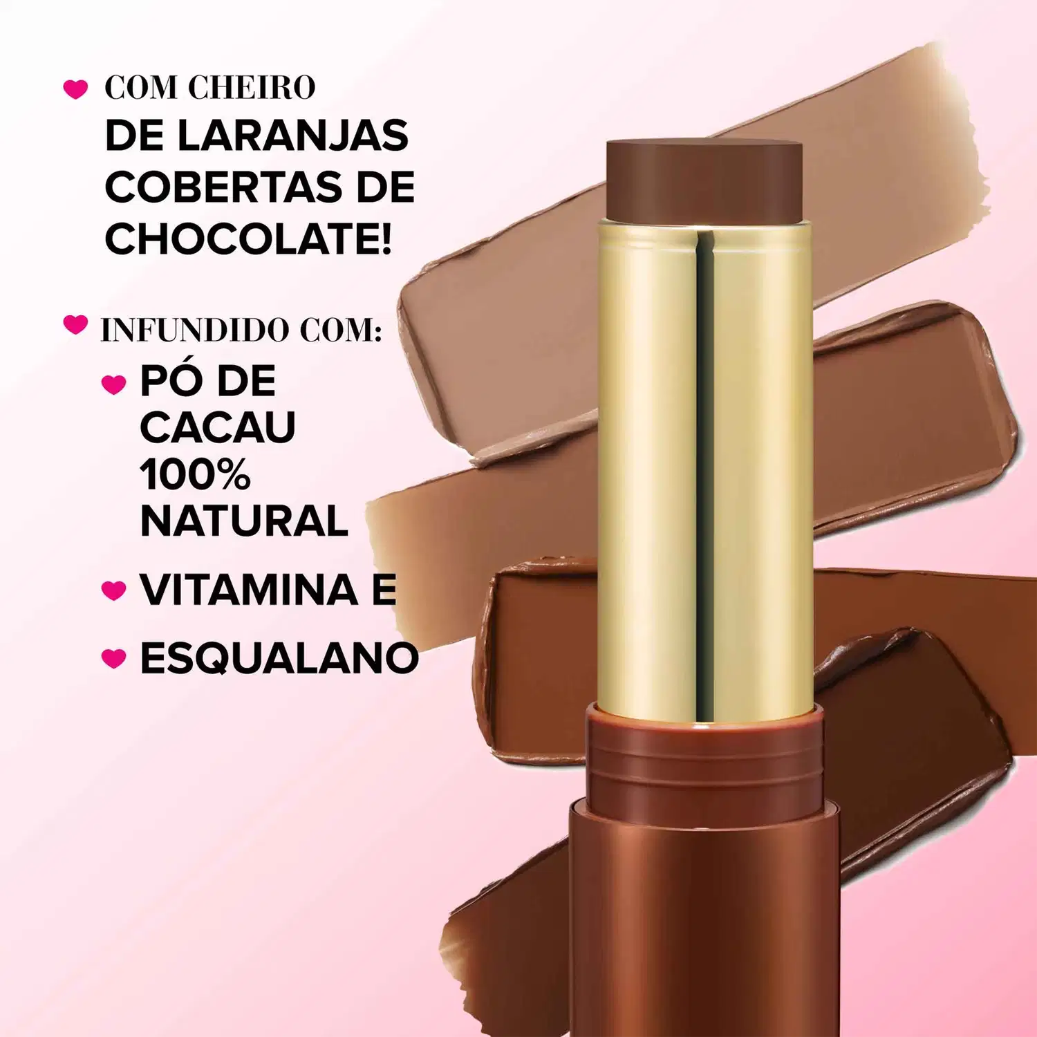 Bronzer em Bastão com embalagem dourada e detalhes marrom-avermelhados. A embalagem apresenta um rótulo em português com os dizeres "Com cheiro de laranjas cobertas de chocolate!" e lista os ingredientes "Pó de cacau 100% natural, Vitamina E, Esqualano".