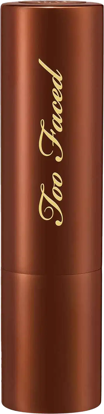 Bronzer em Bastão cilíndrico de metal cor marrom. O frasco tem uma tampa arredondada da mesma cor. O nome da marca "Too Faced" está escrito em letras douradas cursivas no corpo do frasco. O produto tem um acabamento metálico brilhante.