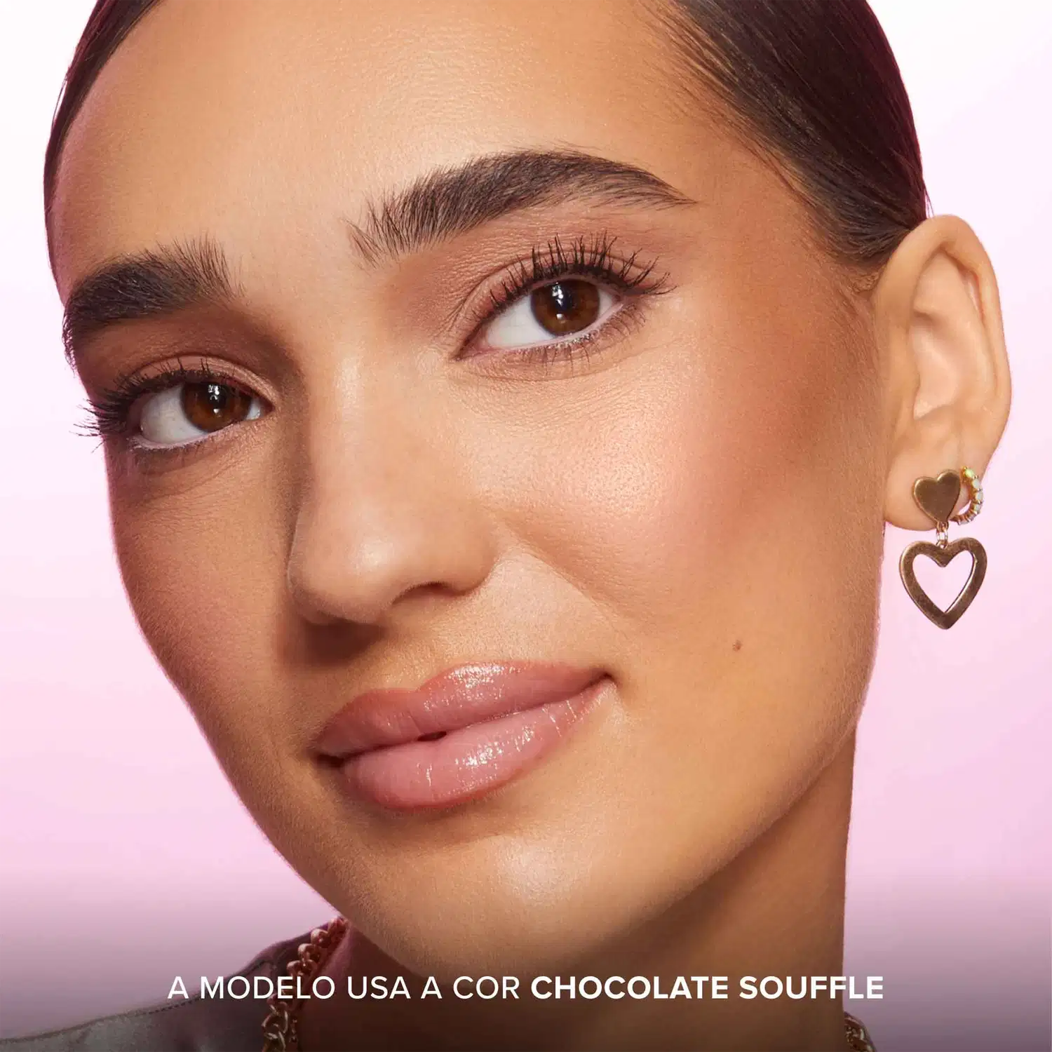 A imagem mostra uma modelo usando maquiagem da linha Too Faced. Ela tem pele bronzeada e olhos castanhos marcantes realçados com maquiagem em tons terrosos.  O texto na parte inferior indica que ela usa o produto "Cor Chocolate Souffle" da marca.