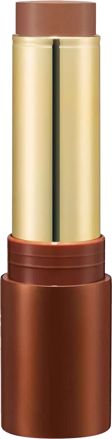 Bronzer em Bastão em embalagem cilíndrica. O estojo é de metal dourado com detalhes em tom de marrom. A parte superior e inferior são de cor cobre fosco. A embalagem tem um design elegante e sofisticado.