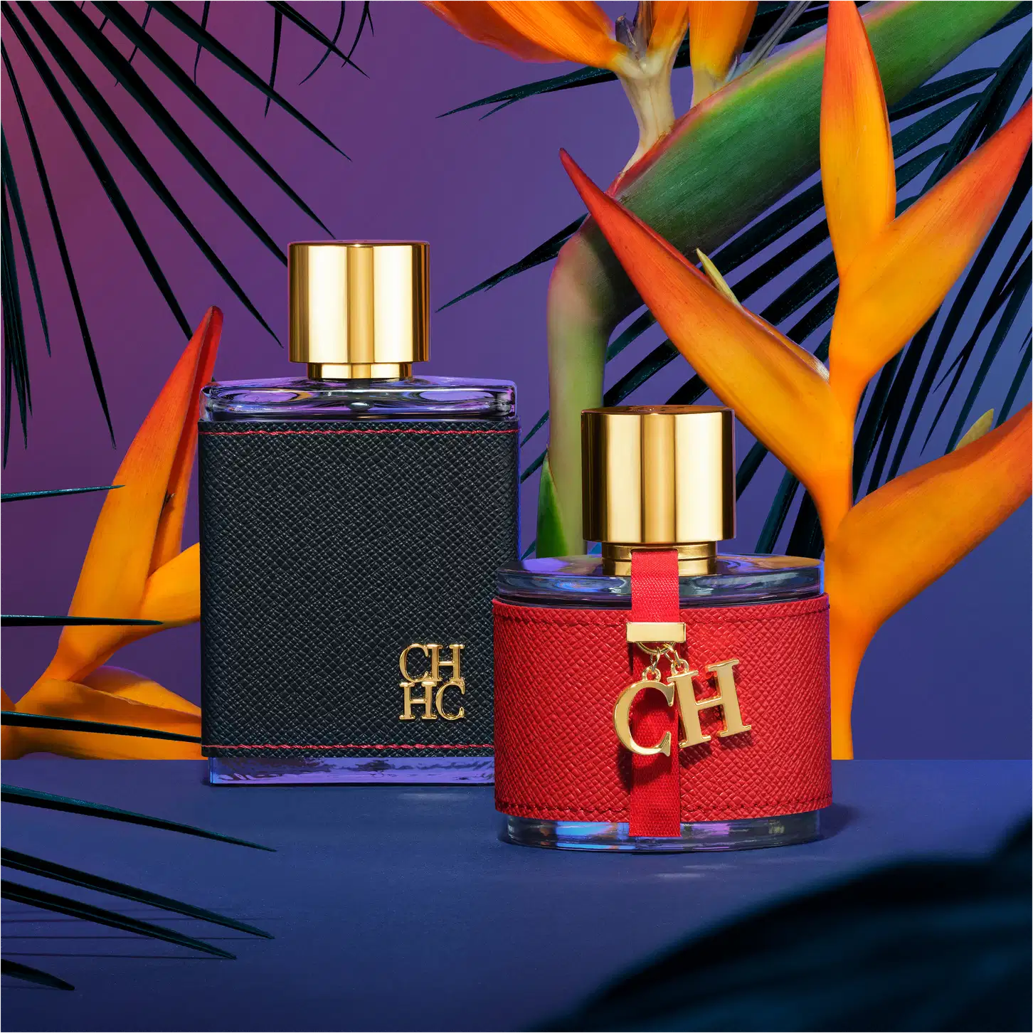 A imagem mostra dois frascos de perfumes, da mesma coleção. Um maior, retangular, com capa preta e tampa dourada, e um menor, arredondado, com capa vermelha e tampa dourada. Ambos apresentam a logo da marca em alto relevo.