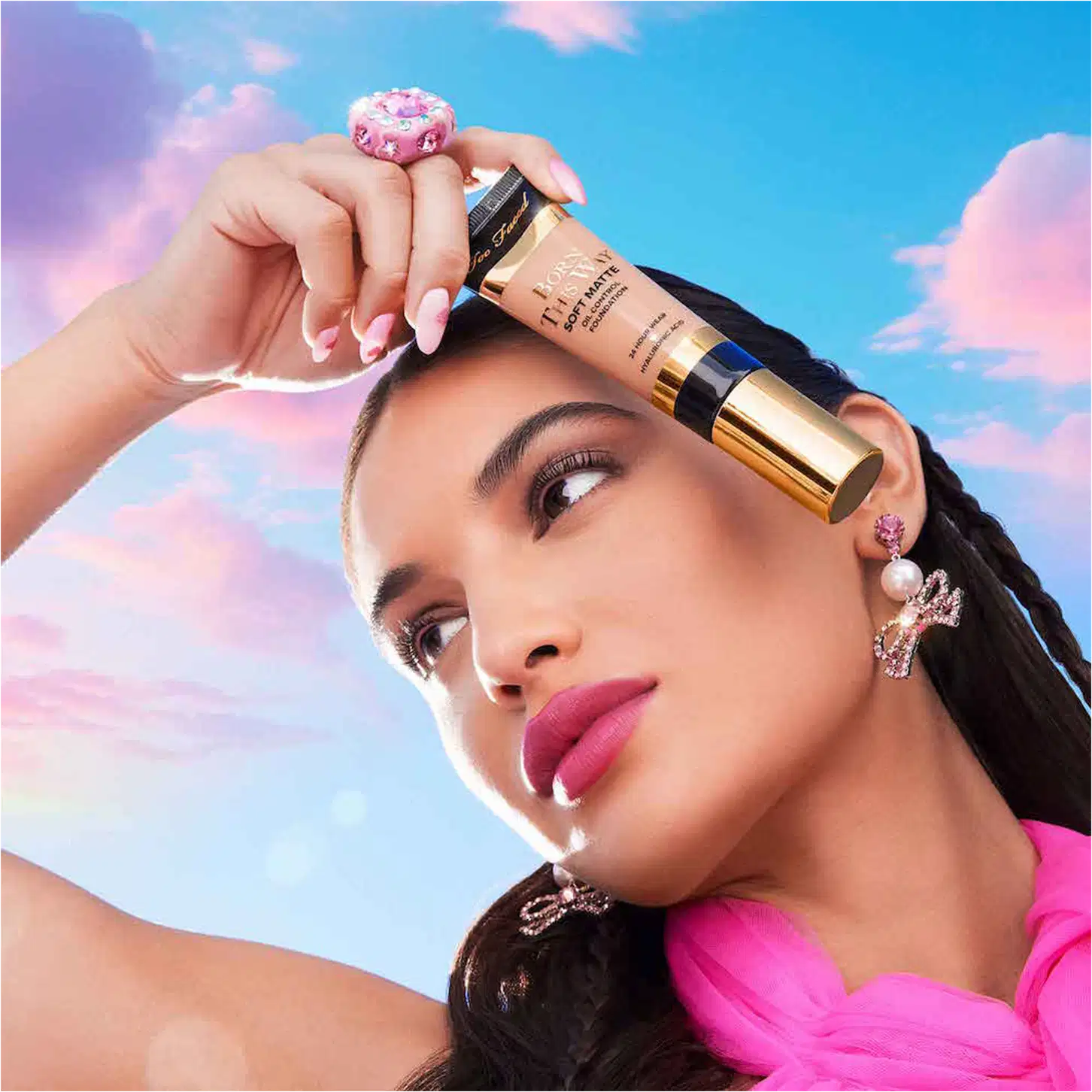 A imagem mostra uma mulher super produzida segurando uma embalagem da base próxima ao rosto.
