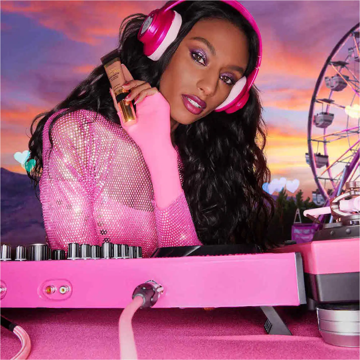 A imagem mostra uma mulher super produzida, com fone de ouvido e uma mesa de dj, ambos de cor rosa, segurando uma embalagem da base próxima ao rosto.