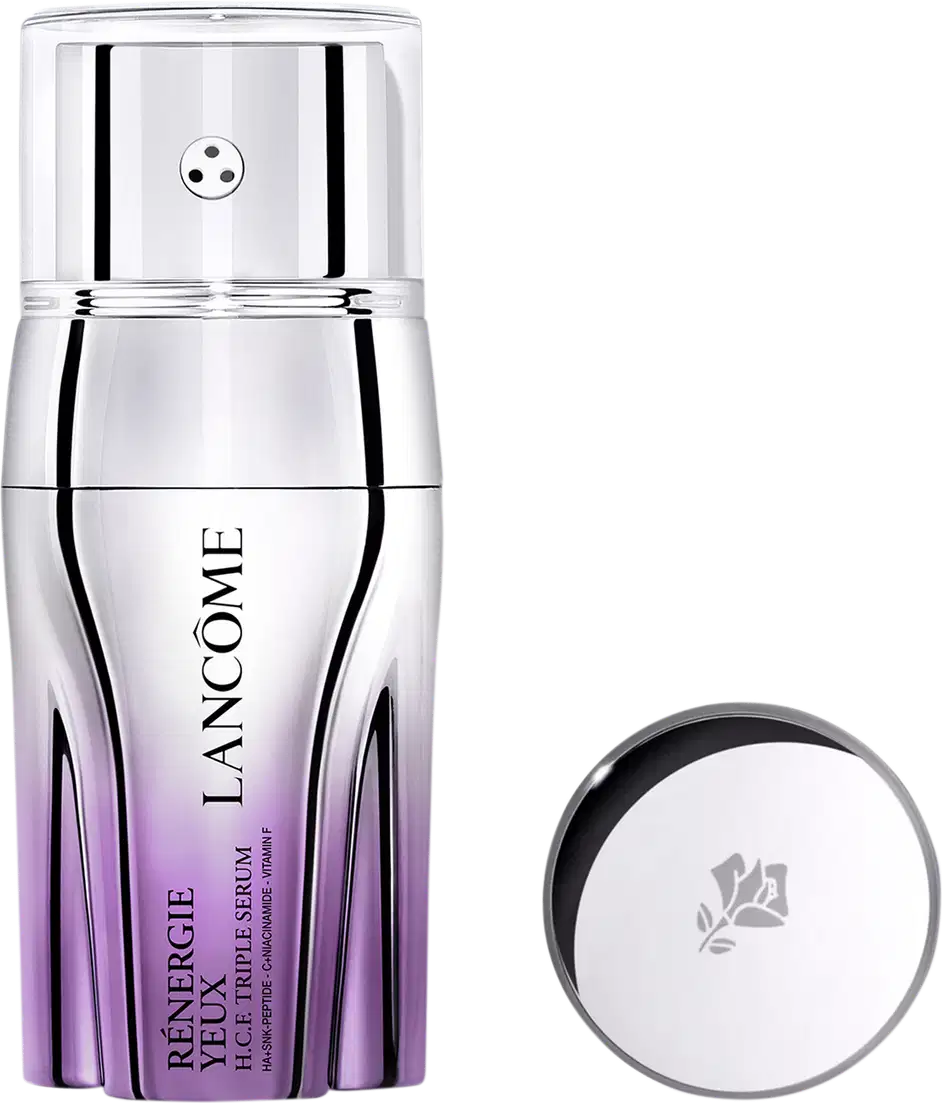 Sérum em frasco cilíndrico com degradê de roxo na base. O frasco tem tampa prateada com pequeno orifício central. Ao lado, tampa prateada redonda com logotipo floral gravado. Embalagem minimalista com nome do produto e marca visíveis no frasco.