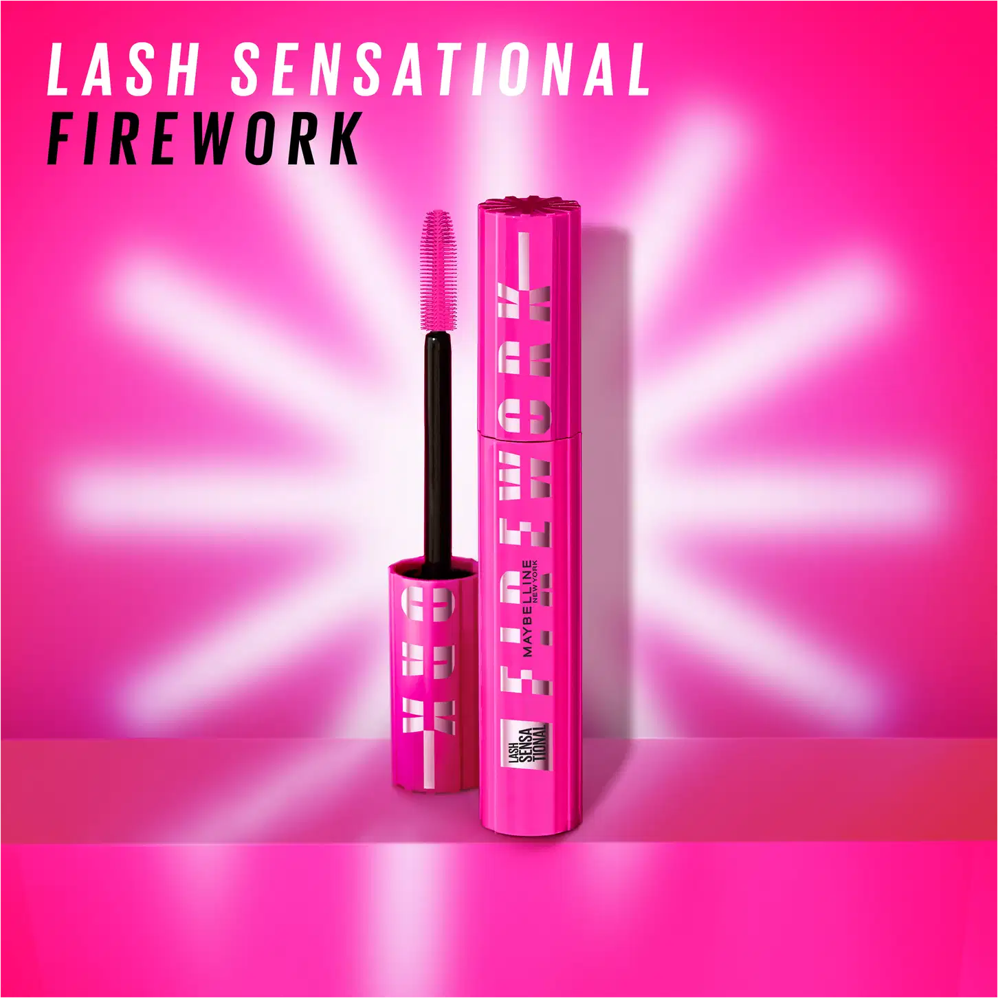 A embalagem tem um design moderno e chamativo, com um fundo rosa brilhante e raios de luz estilizados irradiando do centro, criando um efeito visual impactante. O texto "Lash Sensational Firework" está escrito em letras pretas.