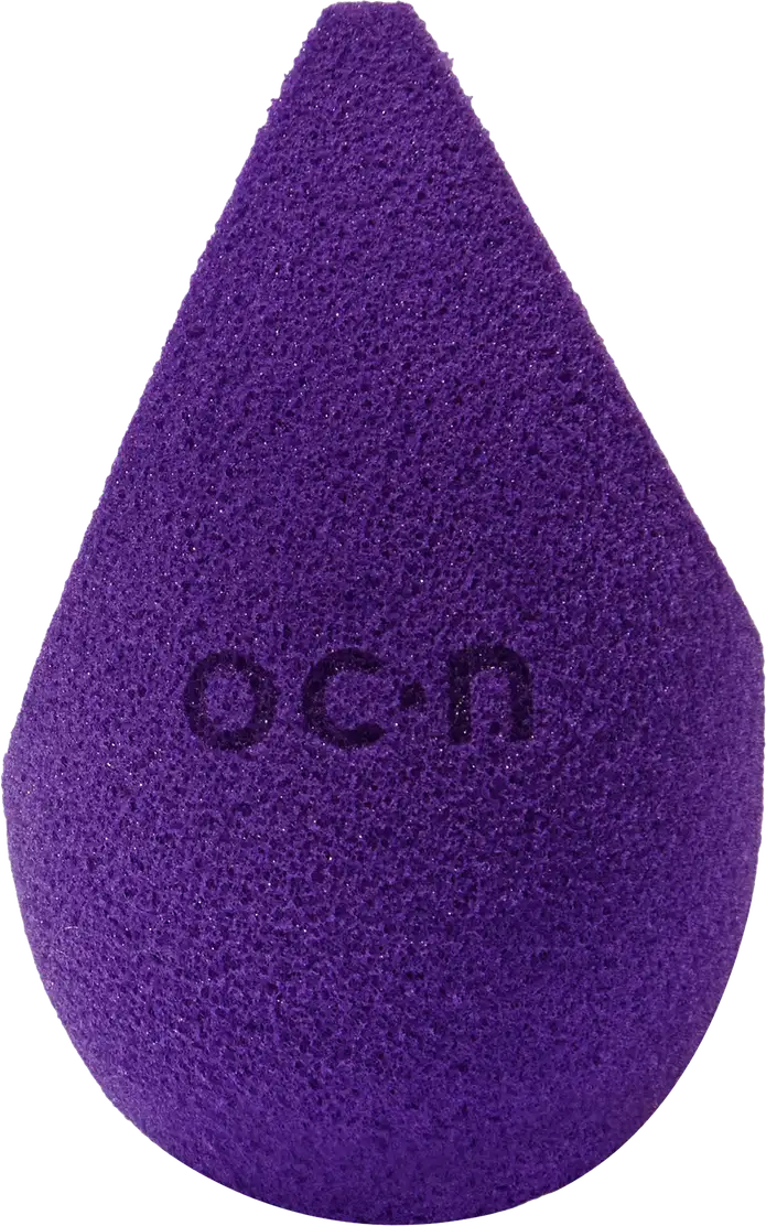 Esponja de maquiagem roxo escuro com textura aveludada. Formato de gota com a palavra "Océane" impressa em relevo na superfície.