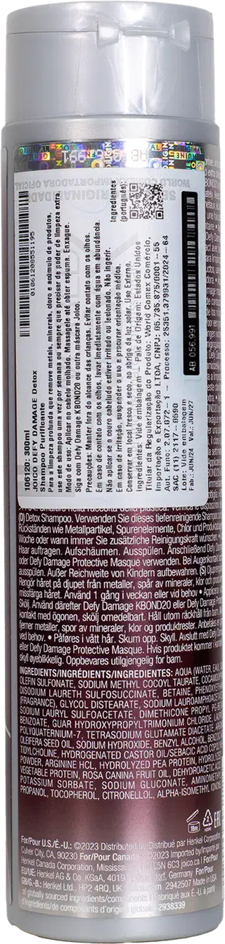 Frasco cilíndrico branco de plástico para shampoo da marca Joico. O rótulo contém informações detalhadas sobre o produto, incluindo ingredientes e instruções, em várias línguas. O frasco tem tampa prata e apresenta as cores branca e roxa.