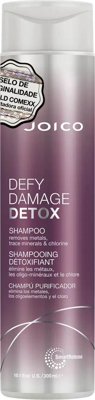 Shampoo detox Defy Damage da marca Joico. Embalagem cilíndrica roxa com detalhes prateados. Rótulo indicando que remove metais, minerais traço e cloro dos cabelos. Volume de 10.1 fl oz / 300ml.