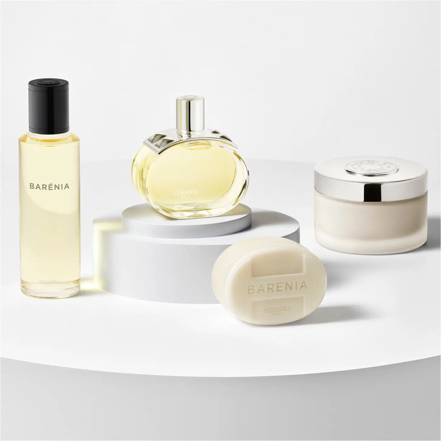 A imagem mostra uma seleção de produtos de Barénia, um refil, o frasco do perfume, um sabonete e um pote redondo com a tampa prateada.