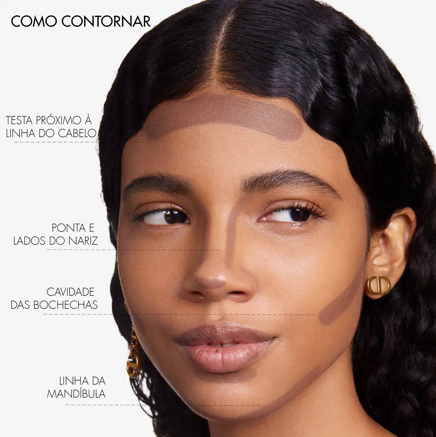 A imagem mostra uma mulher com traços étnicos, pele morena e cabelos escuros. Ela tem olhos castanhos marcantes e lábios cheios e brilhantes. A imagem destaca diferentes áreas do rosto, guiando as áreas de aplicação.