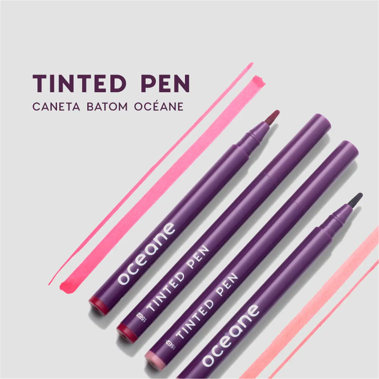 Tinted Pen, caneta batom da marca Océane. Conjunto de quatro canetas com embalagens roxas.. As canetas apresentam o nome da marca "Océane" e "Tinted Pen" impressos em letras brancas. O fundo da imagem tem listras diagonais em tons de rosa e vermelho claro