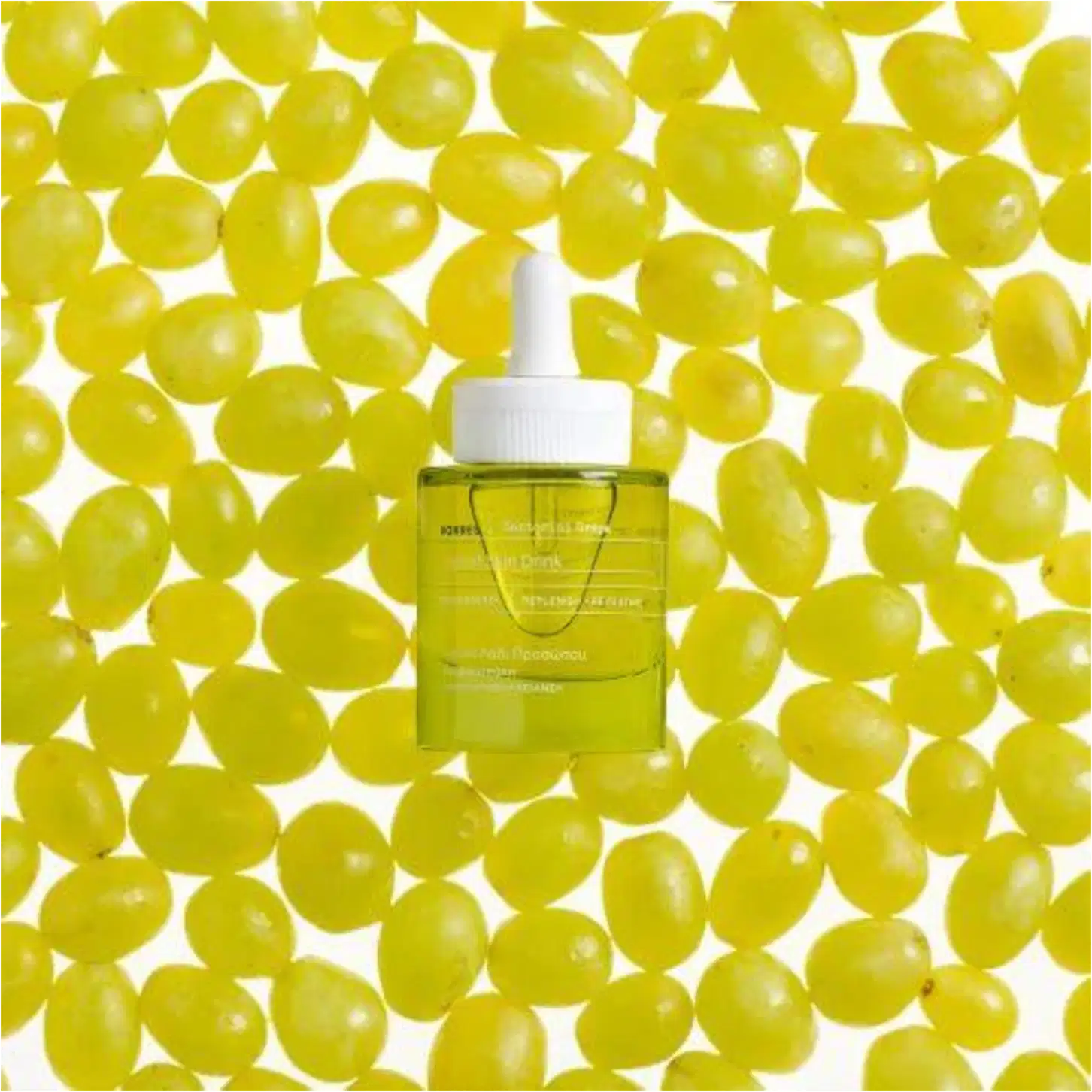 A imagem mostra o frasco do sérum rodeado de uvas verdes.