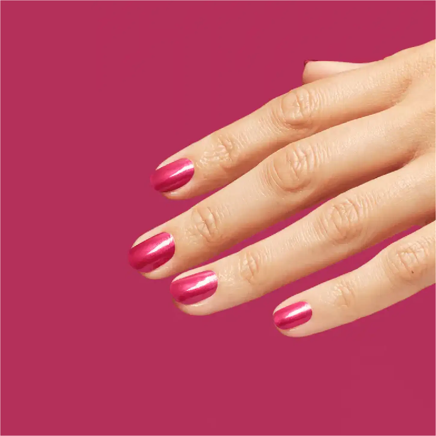 Uma mão feminina pintada com o esmalte. Fundo rosa pink.