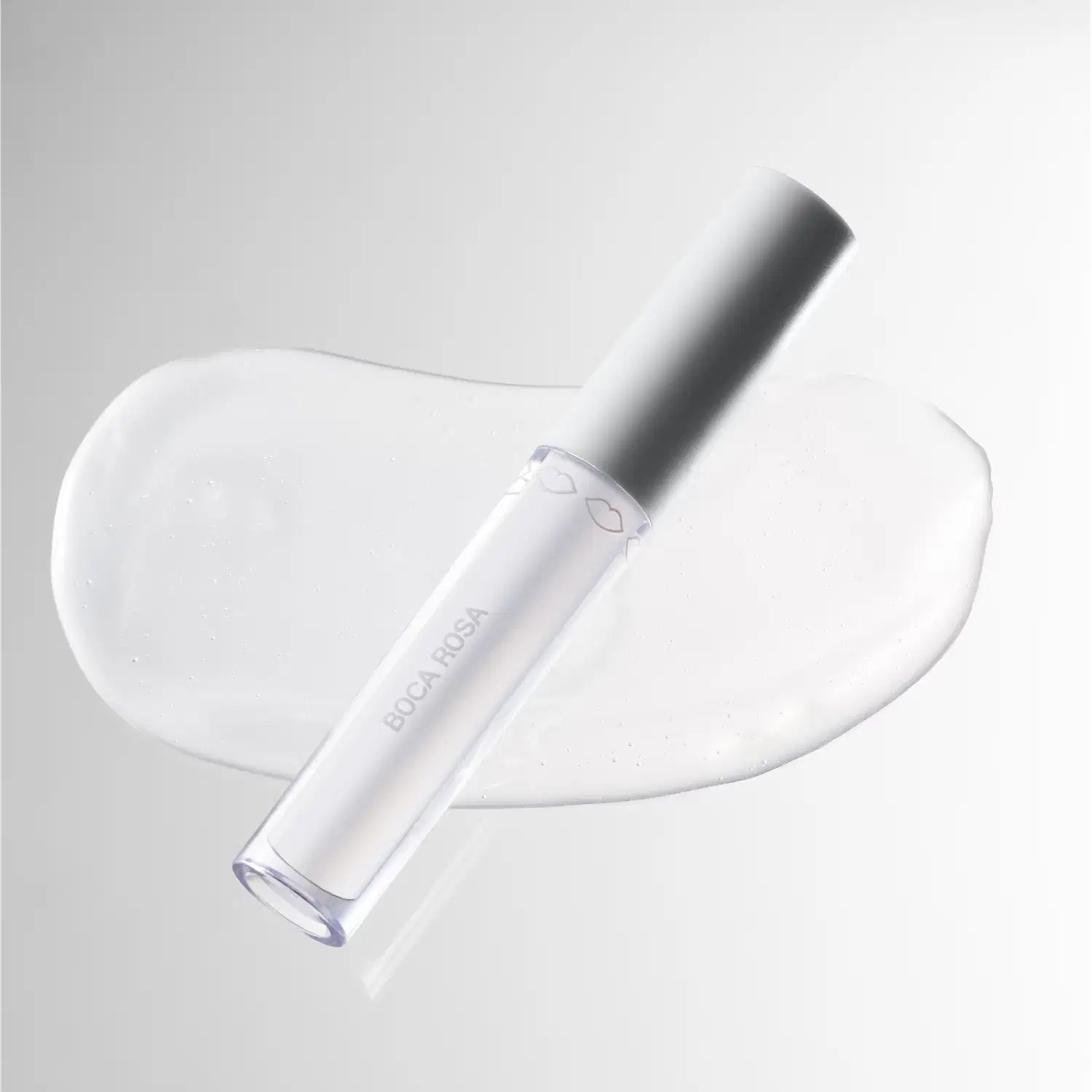 A imagem mostra o Gloss Boca Rosa Hidra Lábios Natural Translúcido e a cor e textura ao fundo