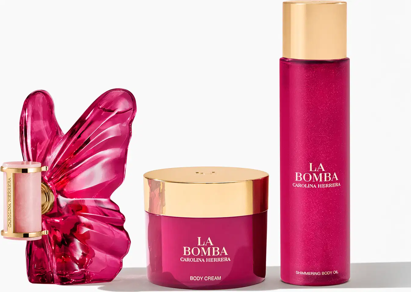 Conjunto de produtos de beleza da marca Carolina Herrera, incluindo um frasco de perfume com tampa dourada, um pote de creme corporal rosa e um frasco de óleo corporal brilhante, todos com embalagens em tons de rosa e detalhes dourados.