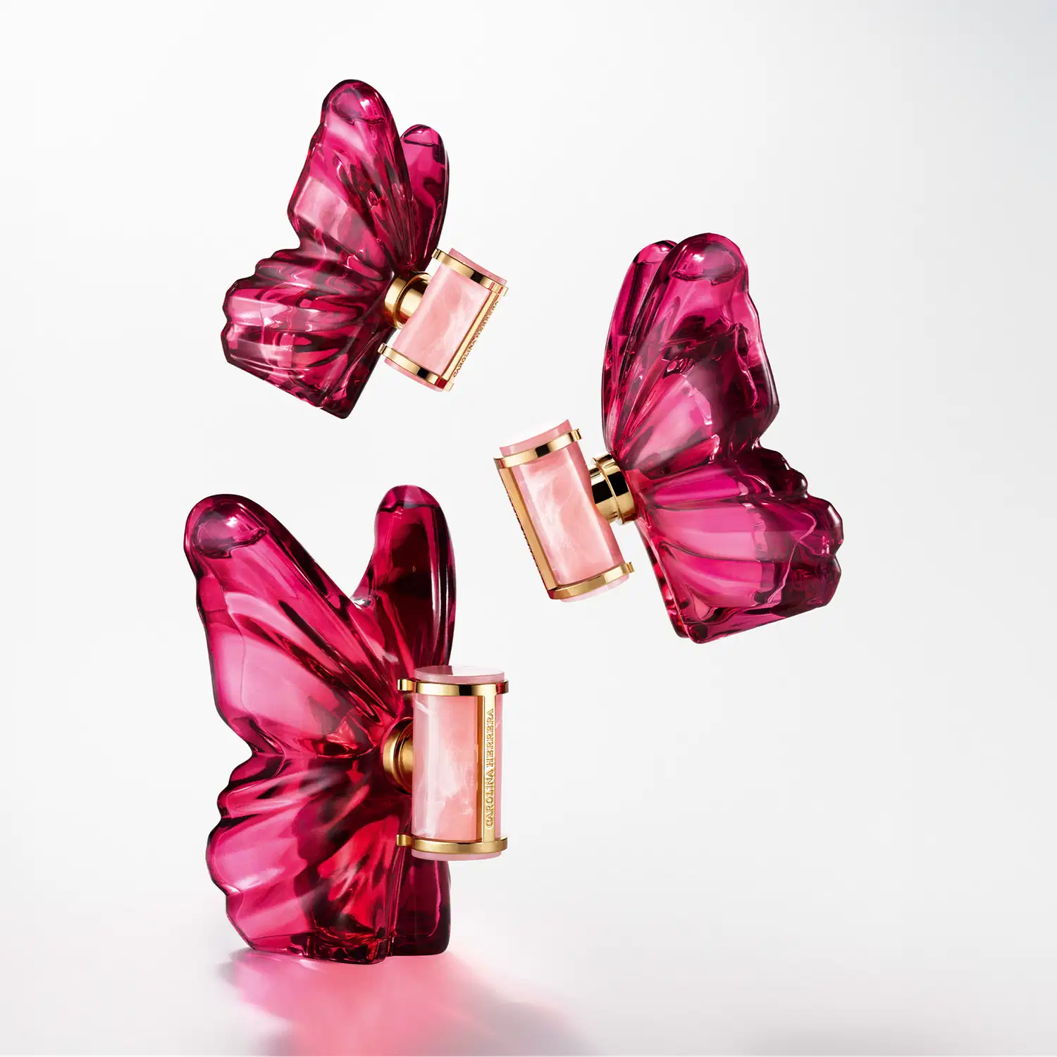 Frasco de perfume Carolina Herrera em formato de borboleta, com tampa dourada e corpo em tom de rosa intenso, destacando a elegância e sofisticação da marca.