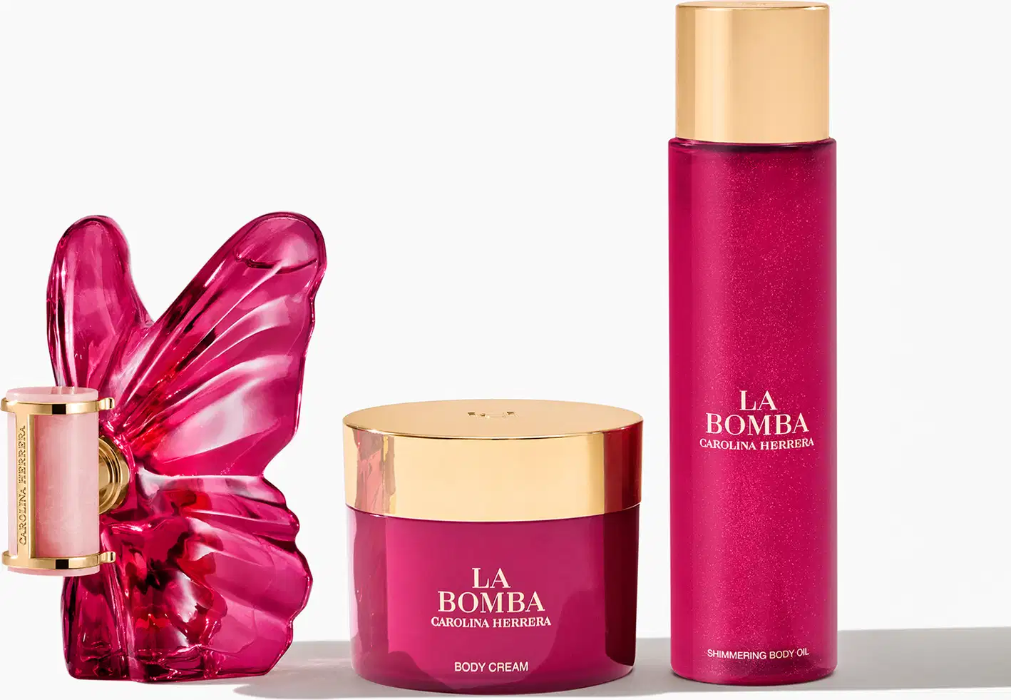 Produtos de beleza da marca Carolina Herrera, incluindo um frasco de perfume com tampa dourada, um pote de creme corporal e um frasco de óleo corporal brilhante, todos em tons de rosa vibrante.