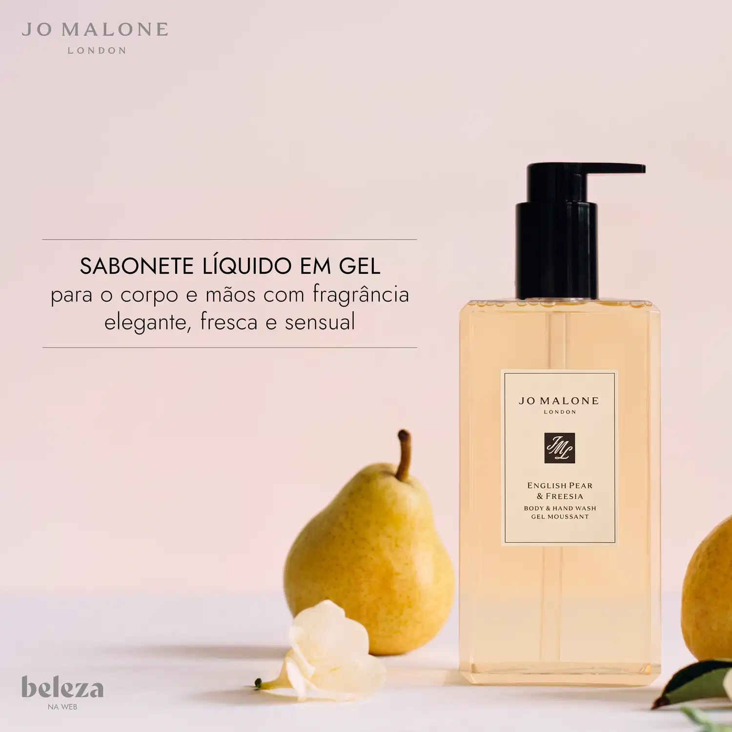 Frasco de item de perfumaria da marca Jo Malone London com rótulo "English Pear & Freesia Body & Hand Wash Gel Moussant" em fundo rosa claro, com uma pera amarela ao lado.