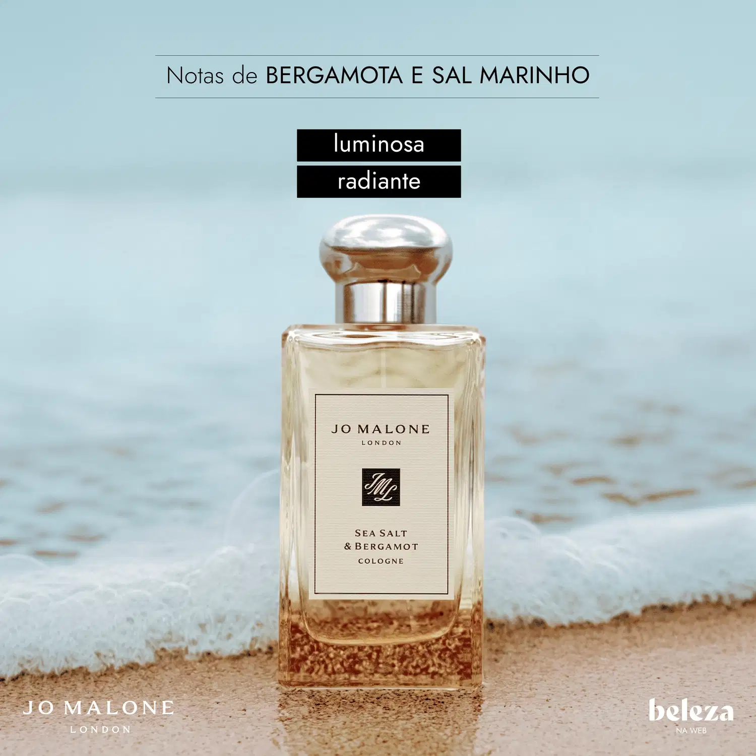 Frasco de item de perfumaria da marca Jo Malone London com rótulo "Sea Salt & Bergamot Cologne" em fundo de praia arenosa e água.