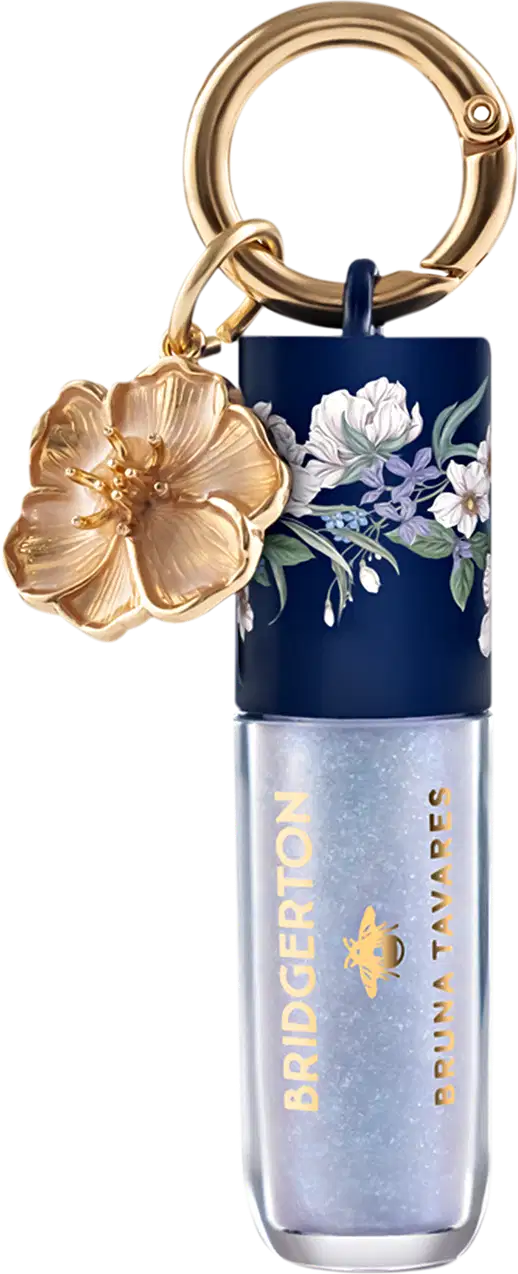 Embalagem de gloss labial da marca Bruna Tavares com textura suave e brilho, na cor Diamond, acompanhada de pingente dourado em formato de flor.
