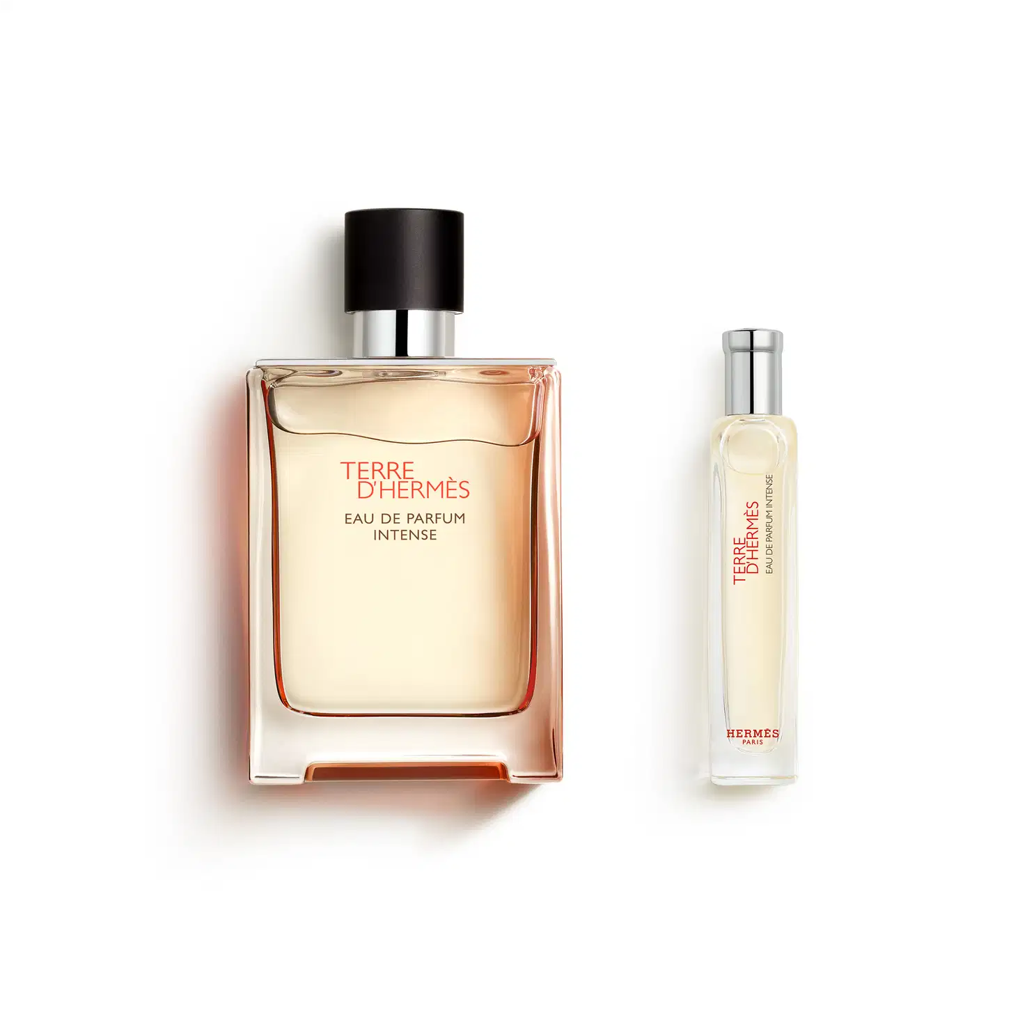 Dois frascos de perfume da marca Hermès: um frasco grande de Terre d'Hermès Eau de Parfum Intense com embalagem em tons de laranja e um frasco menor de Terre d'Hermès, ambos com rótulos e detalhes em preto e prata.
