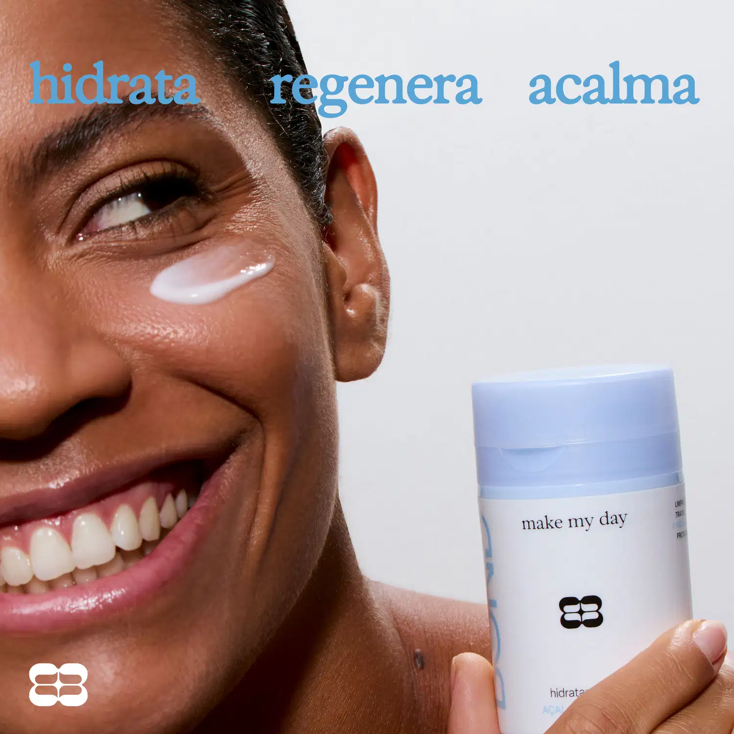 Rosto sorridente de uma pessoa com texto "hidrata", "regenera" e "acalma" acima, segurando um item de perfumaria com a marca "make my day" visível na embalagem.