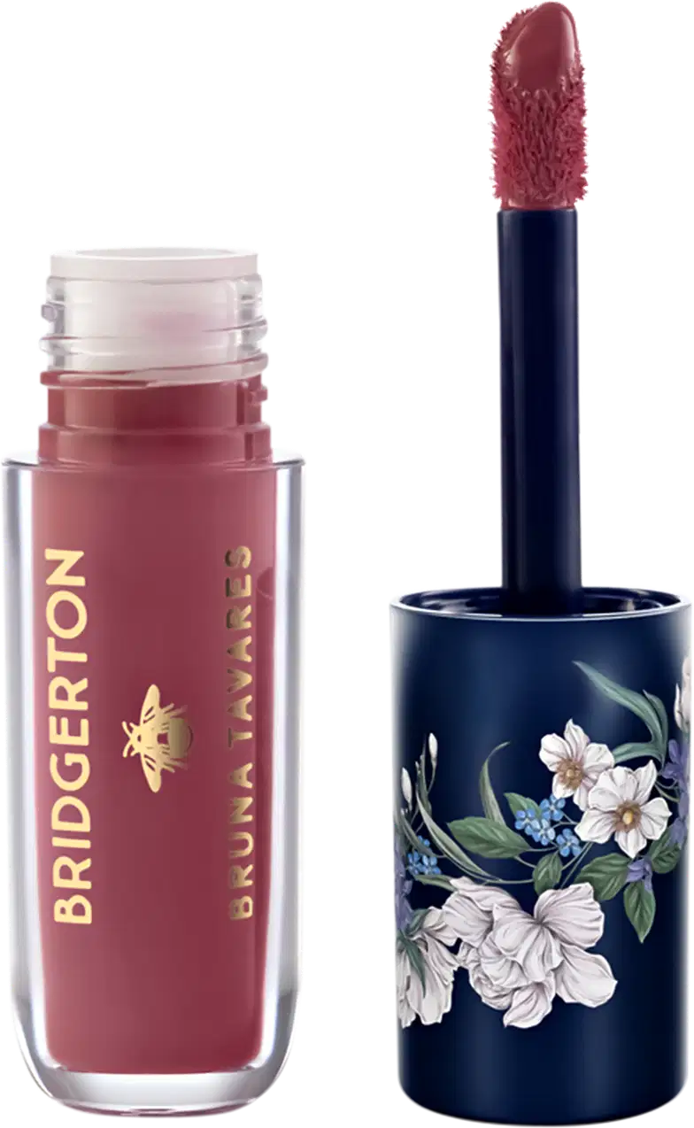 Embalagem de item de maquiagem da marca Bruna Tavares em tom vermelho-rosado com aplicador de espuma, acompanhada de embalagem decorada com flores brancas e azuis em fundo azul-marinho.