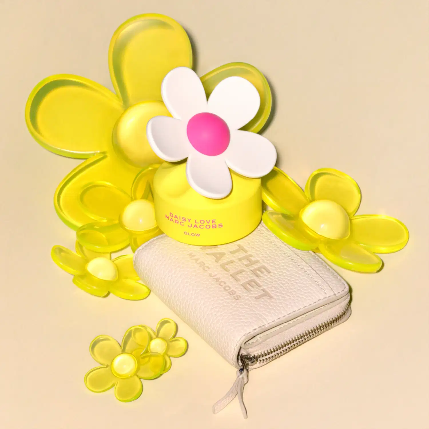 Frasco de perfume em formato de flor branca com centro rosa, embalado em caixa amarela com texto "DAISY LOVE MARC JACOBS GLOW" em vermelho e rosa. Produto de beleza da marca Marc Jacobs.