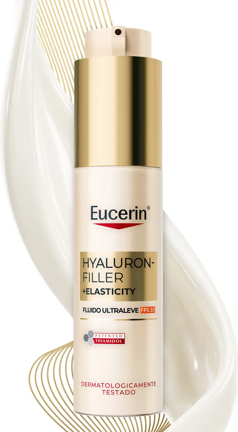 Embalagem dourada e branca de um produto de cuidados com a pele da marca Eucerin, com informações sobre seus benefícios de preenchimento e elasticidade, em um ambiente minimalista e iluminado.
