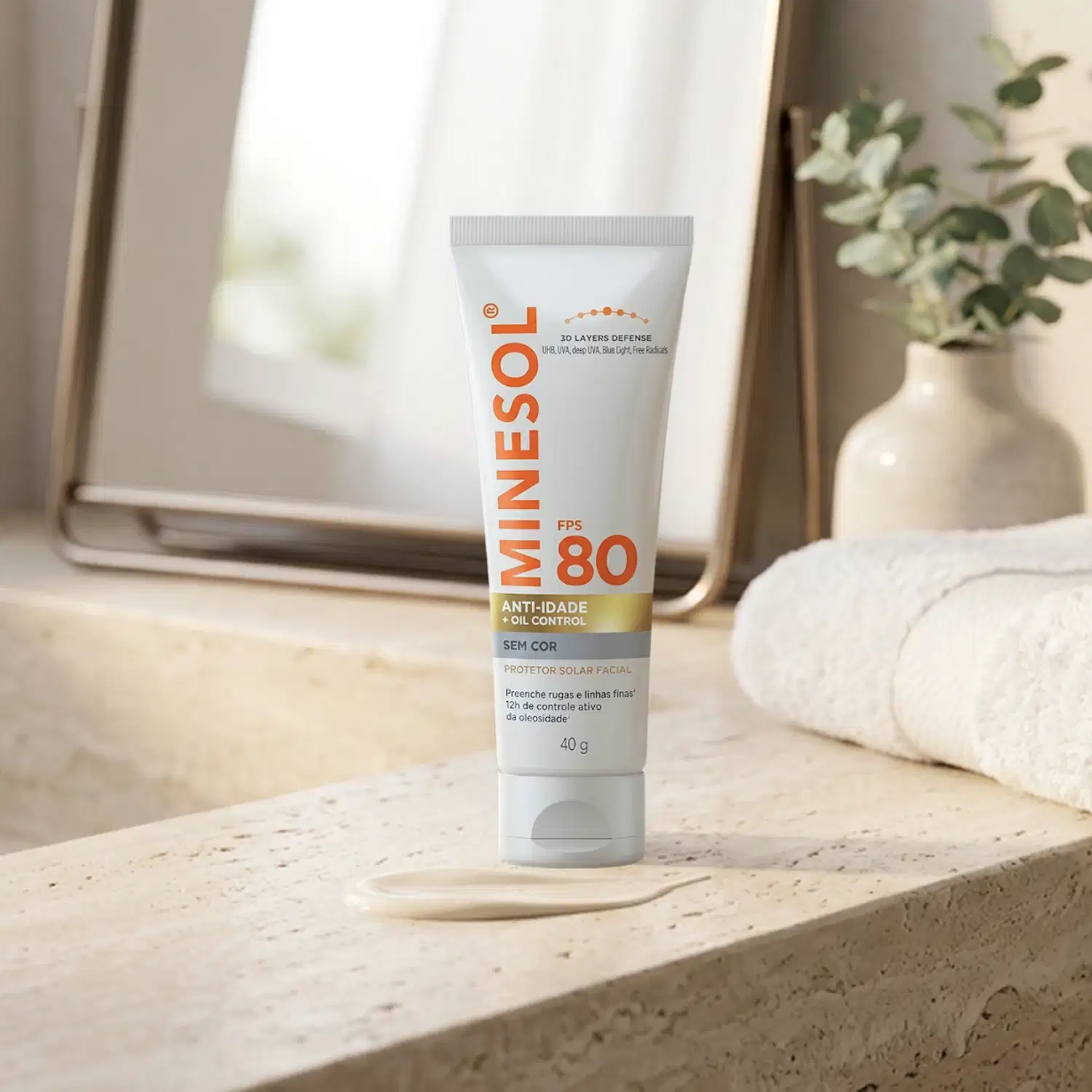 Protetor solar facial Minésol FPS 80 em tubo branco com detalhes em laranja. Embalagem de 40g com indicações de "Anti-idade + Oil Control" e "Sem Cor". Produto posicionado sobre superfície clara com aplicador visível.