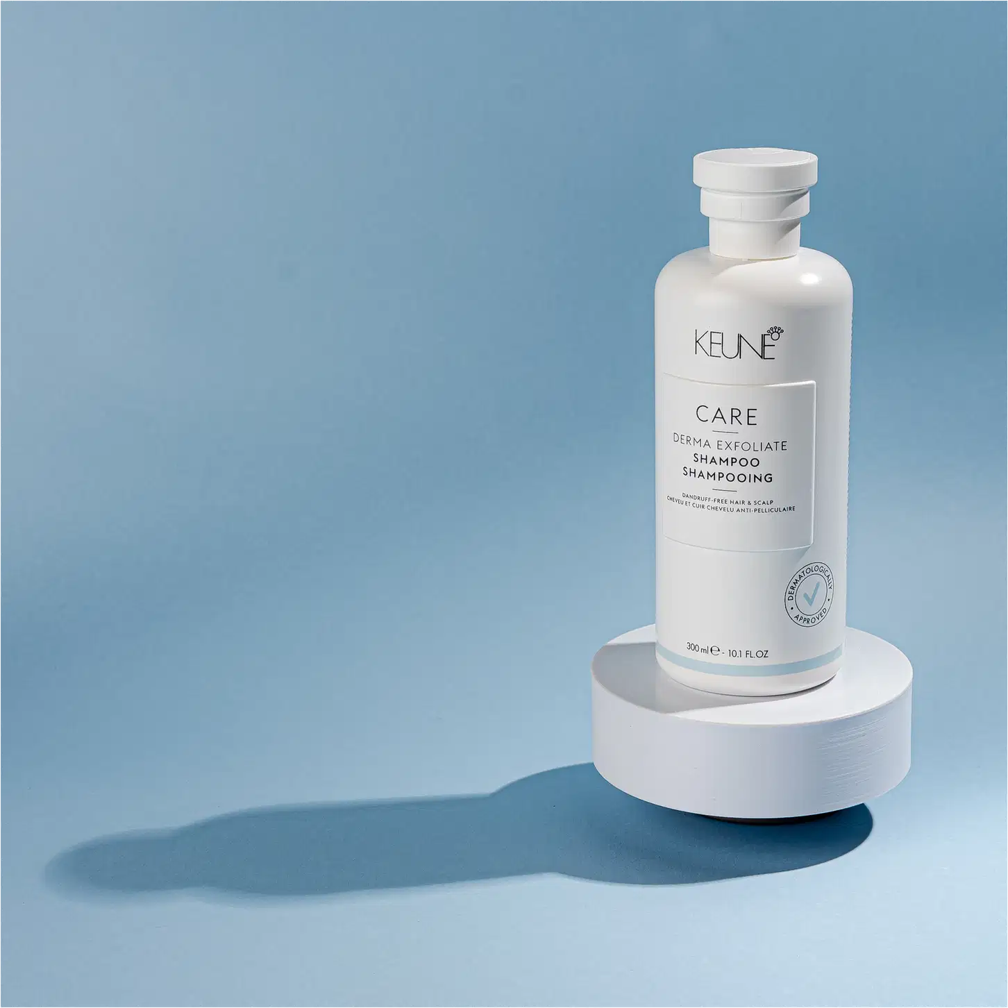 Frasco branco de shampoo Keune Care Derma Exfoliate, com rótulo em preto e branco indicando o nome do produto e sua função de remover caspa do couro cabeludo.