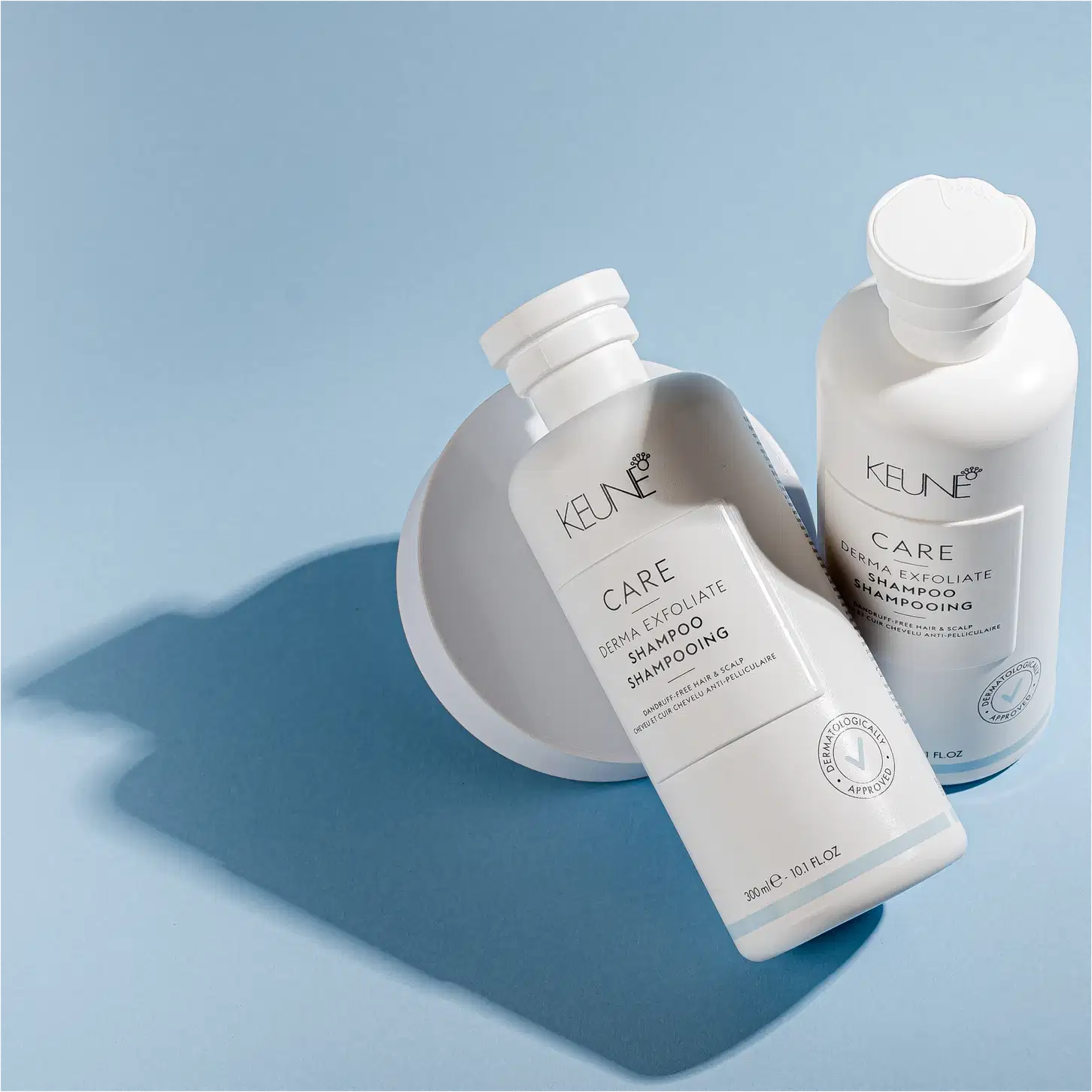 Frasco branco de shampoo Keune Care Derma Exfoliate, com rótulo em preto e branco indicando o nome do produto e sua função de remover caspa do couro cabeludo.