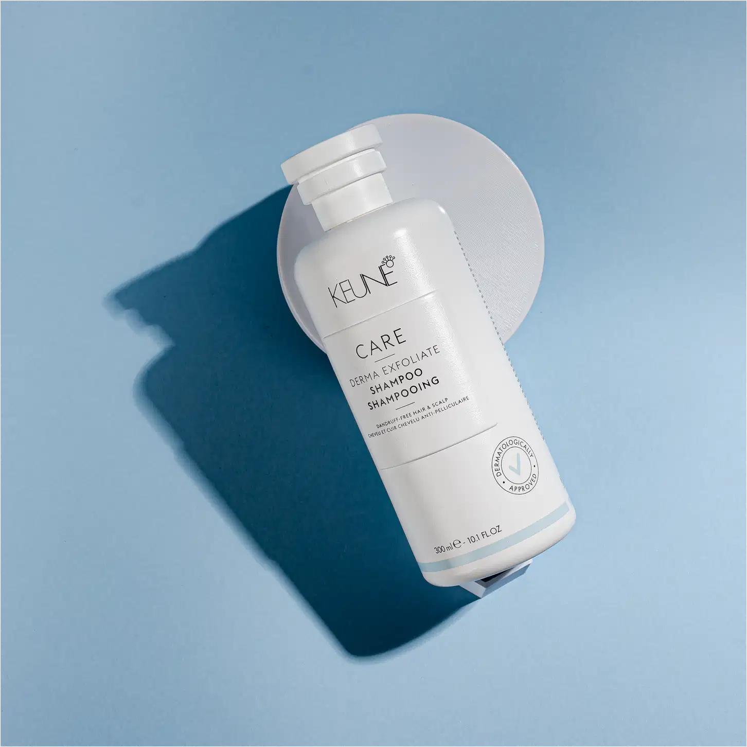Frasco branco de shampoo Keune Care Derma Exfoliate, com rótulo em preto e branco indicando o nome do produto e sua função de remover caspa do couro cabeludo.