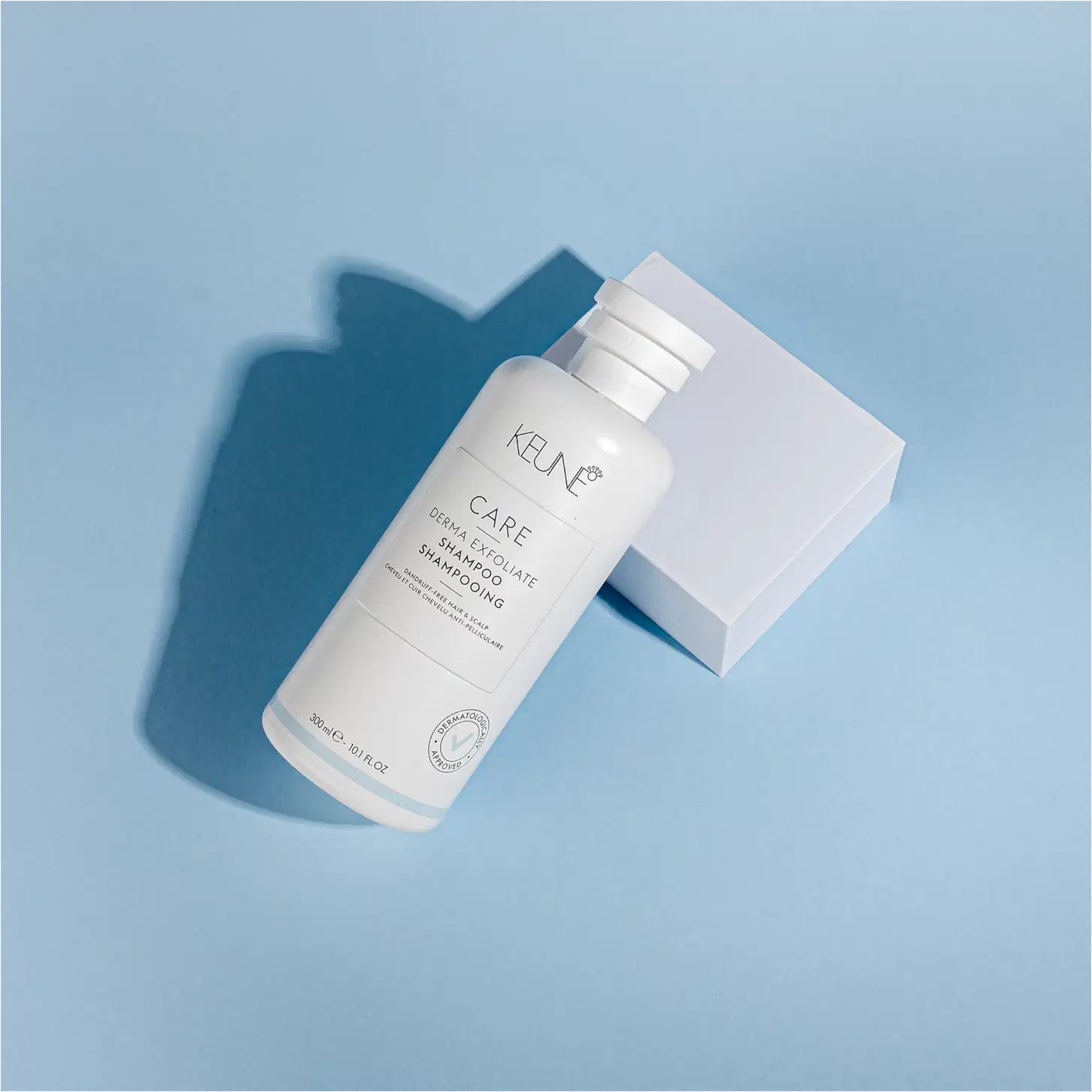 Frasco branco de shampoo Keune Care Derma Exfoliate, com rótulo em preto e branco indicando o nome do produto e sua função de remover caspa do couro cabeludo.