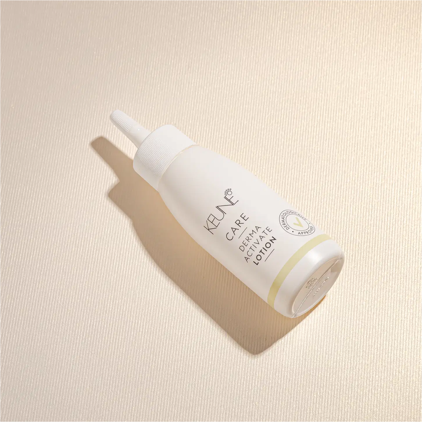 Frasco branco de loção ativadora Keune Care Derma Activate, com rótulo em preto e amarelo, apresentando informações sobre o produto.