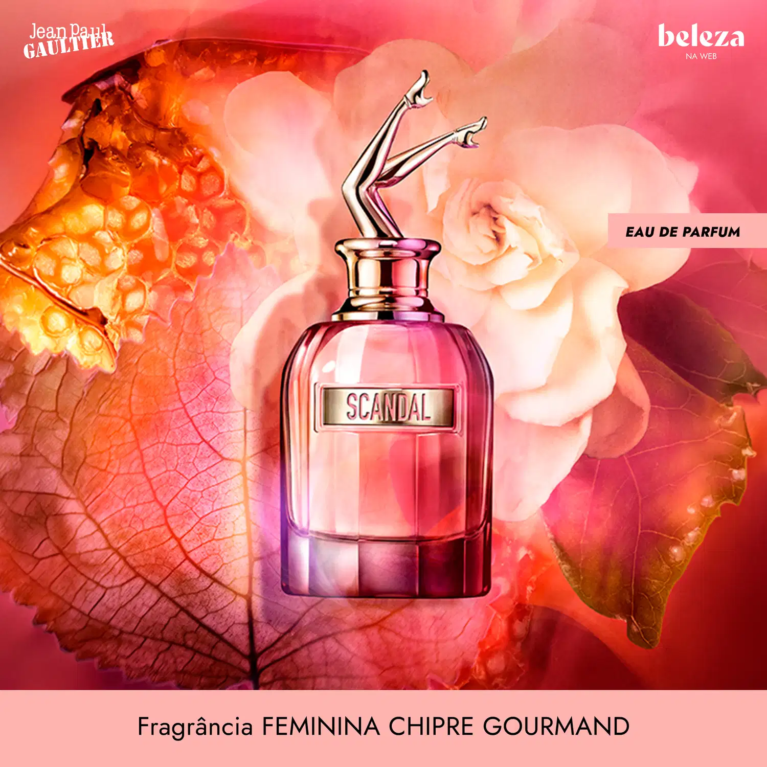 Frasco de item de perfumaria da marca Jean Paul Gaultier com rótulo "Scandal" em fundo de flores rosas e laranja em tons vibrantes.