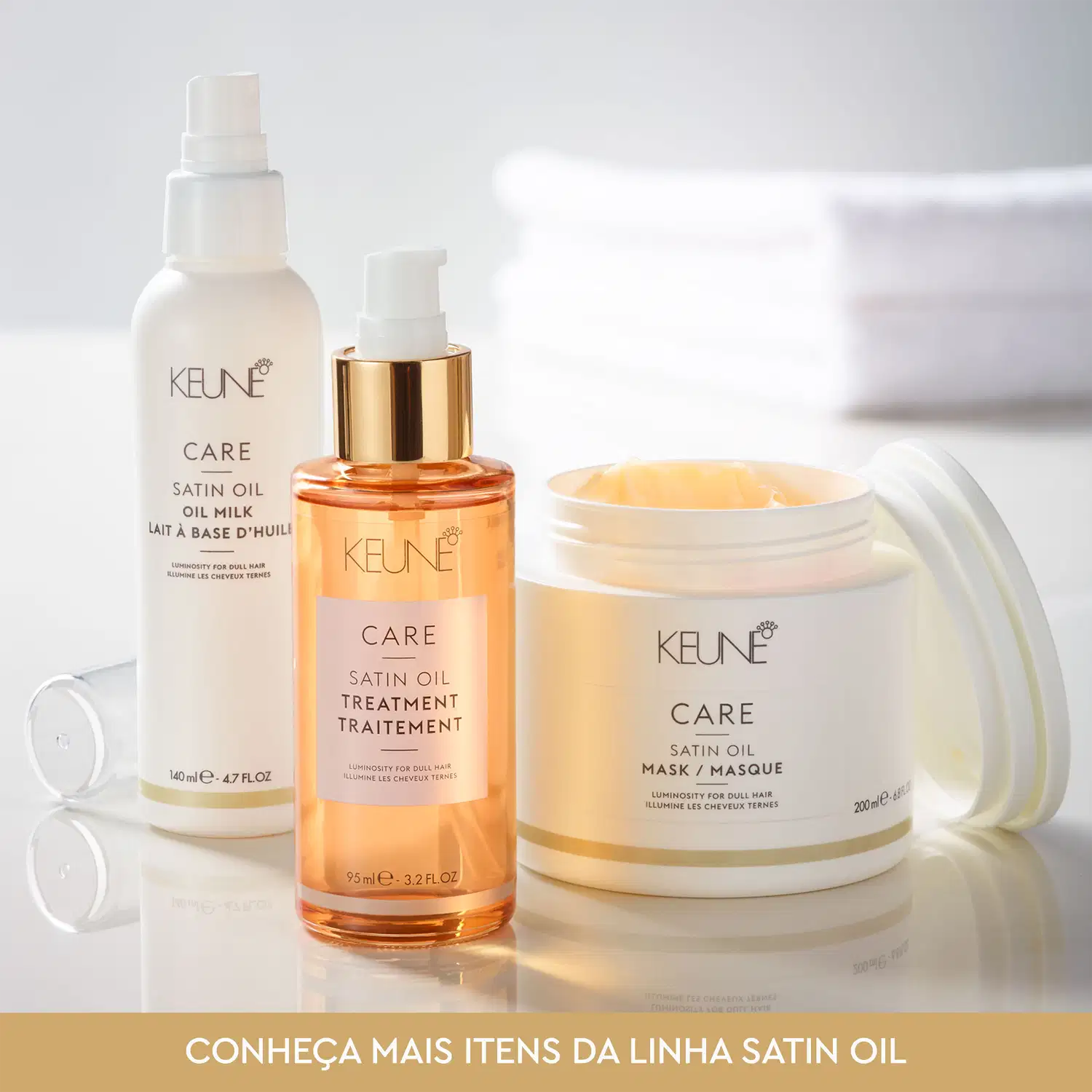 Produtos da linha Satin Oil da Keune, incluindo óleo capilar, tratamento e máscara, em embalagens brancas e douradas com rótulos destacados.