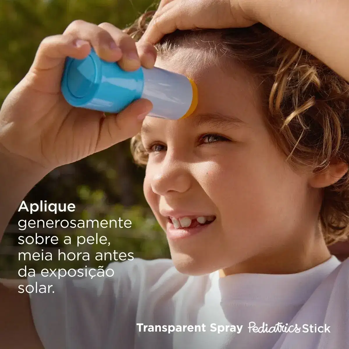 Criança aplicando protetor solar em spray transparente na testa sob luz solar natural, com fundo desfocado em tons verdes.