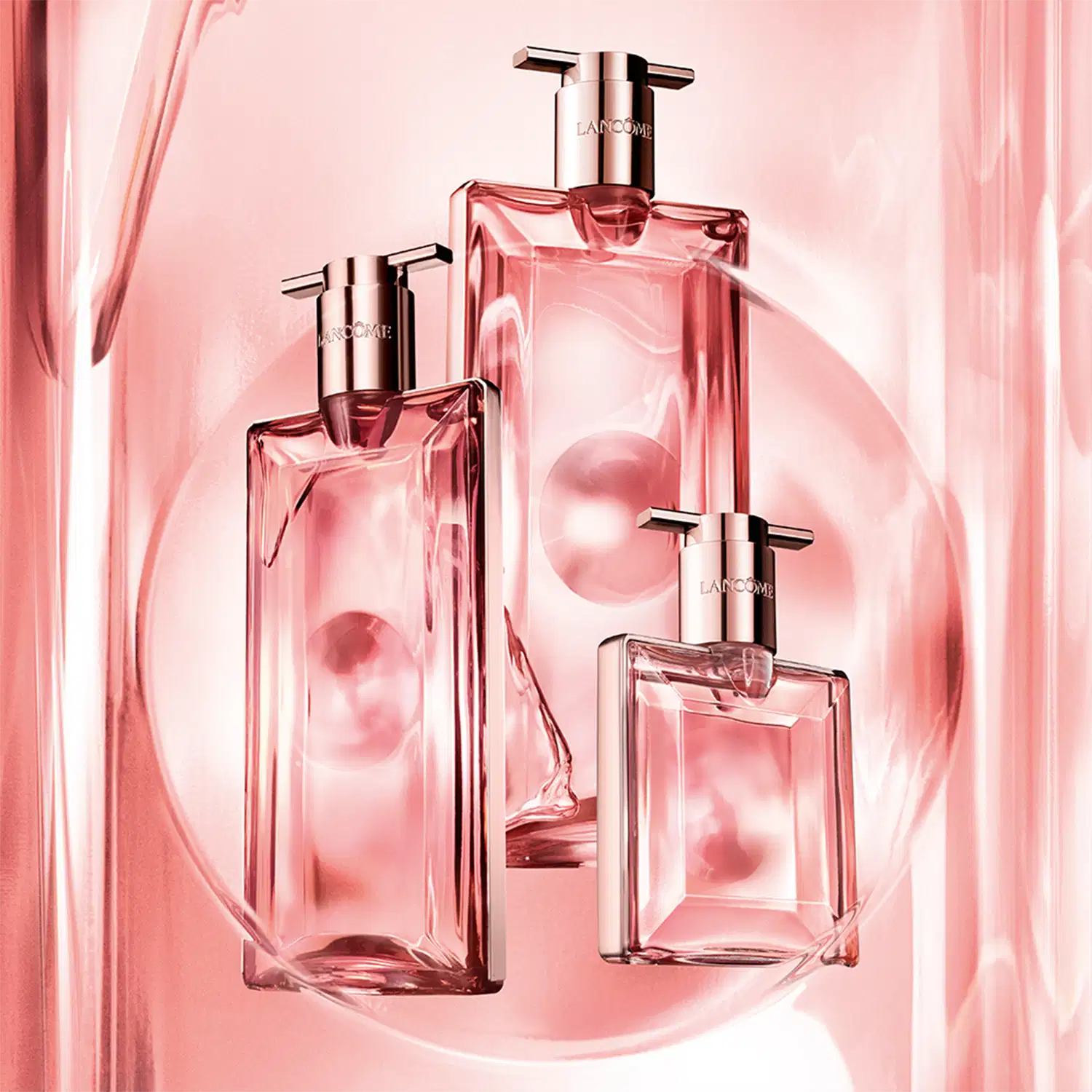 Três frascos de perfume Lancôme em tons de rosa, com design elegante e sofisticado. Os frascos apresentam formatos geométricos e detalhes metálicos, transmitindo uma imagem luxuosa e refinada da marca.