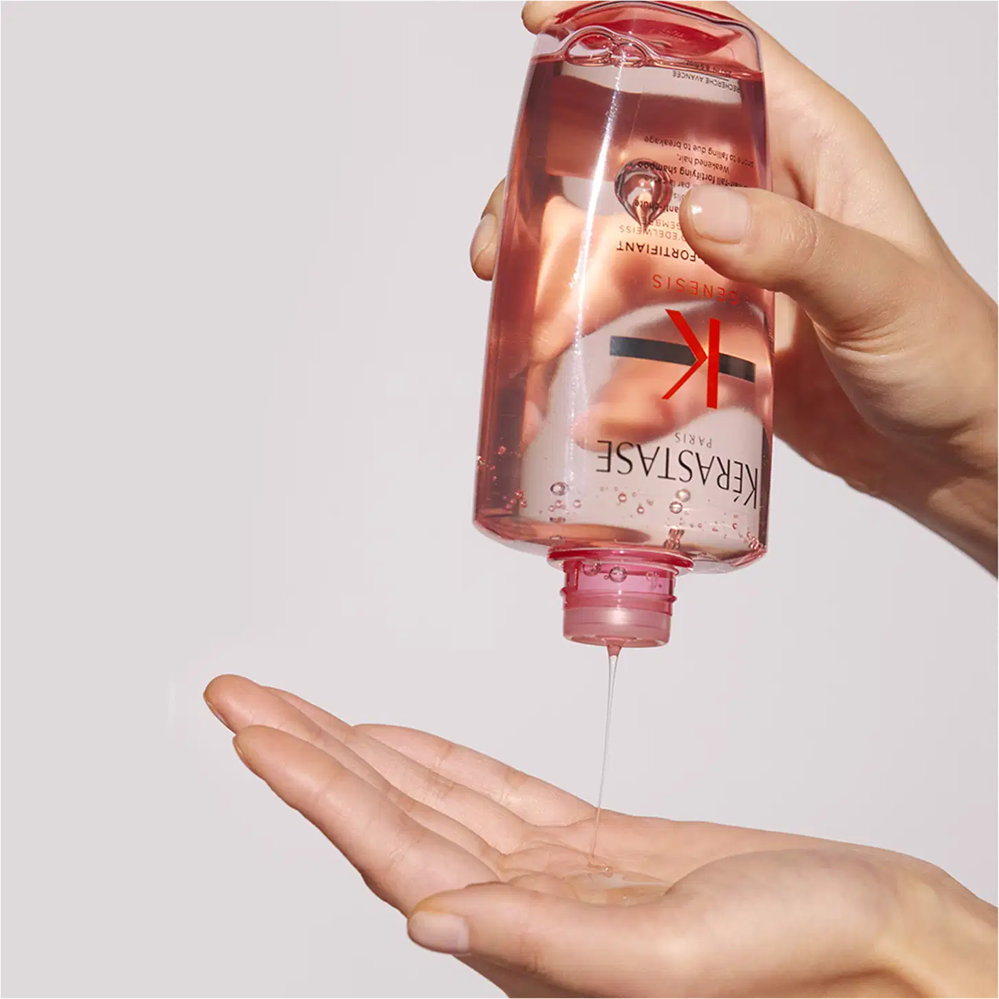 A mão segura um frasco de gel de limpeza facial da marca Neutrogena, com um líquido vermelho transparente escorrendo sobre a palma. O fundo branco e a embalagem vermelha e branca sugerem um ambiente de cuidados de pele e higiene pessoal.