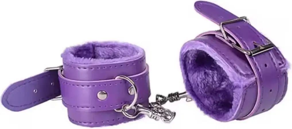 Algemas de couro forradas com pelúcia na cor roxa, com fecho de metal e detalhe em corrente. Produto da marca Sexy Import, destinado a uso adulto.