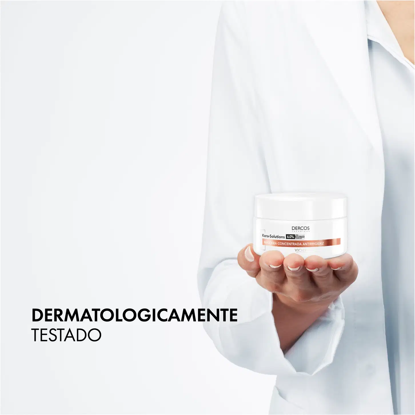 A imagem mostra um profissional de saúde segurando um produto da marca Dercos, que é uma linha de cuidados capilares da Vichy, uma marca de cosméticos e produtos de beleza.
