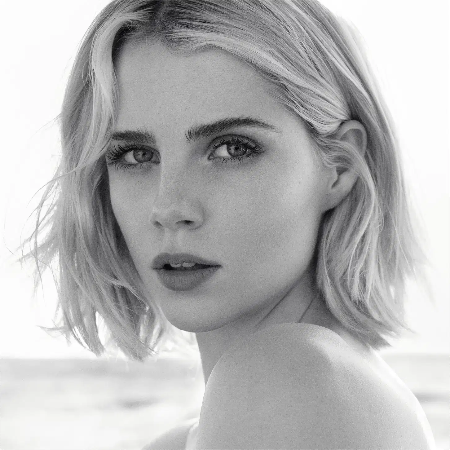 Retrato em preto e branco de uma mulher loira com cabelos curtos e olhar intenso, sugerindo um ambiente de beleza e glamour da marca Chloé.
