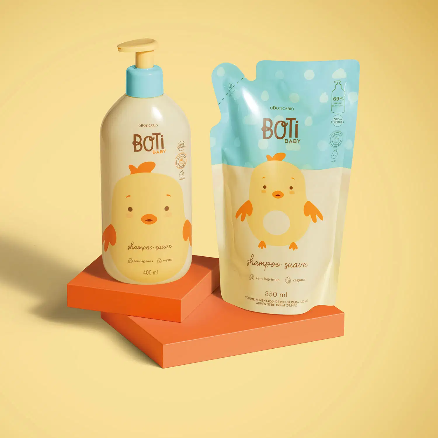 Dois itens Boti Baby em embalagens em tons de amarelo, azul e laranja com ilustração de passarinho amarelo, sendo um frasco com bomba dosadora de shampoo e um refil em sachê sobre plataforma e fundo em tons de laranja.