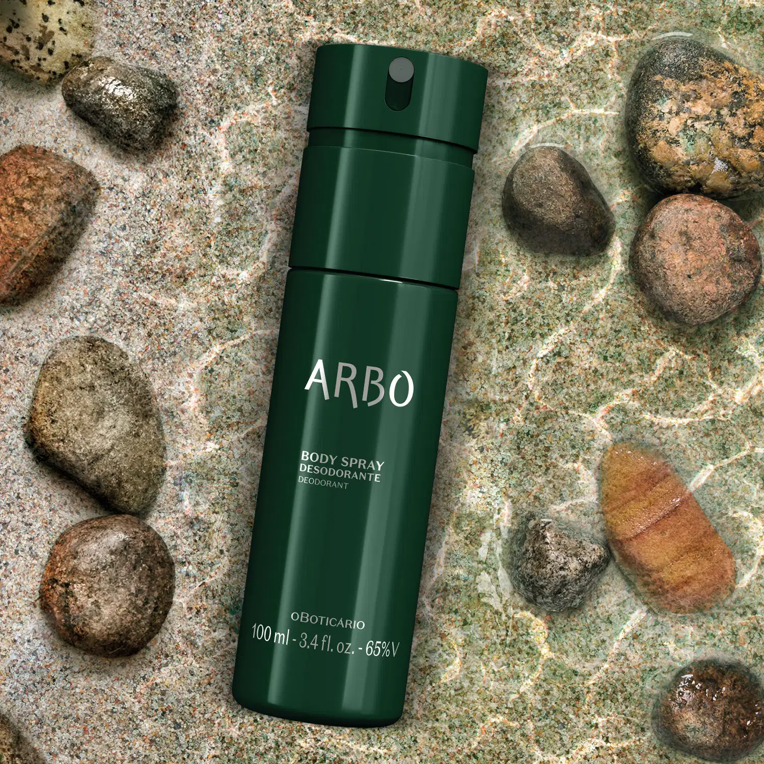 Embalagem verde escura de item de body splash Arbo Forest sobre espelho d'água com pedras no fundo em tons de cinza, em ambiente natural.